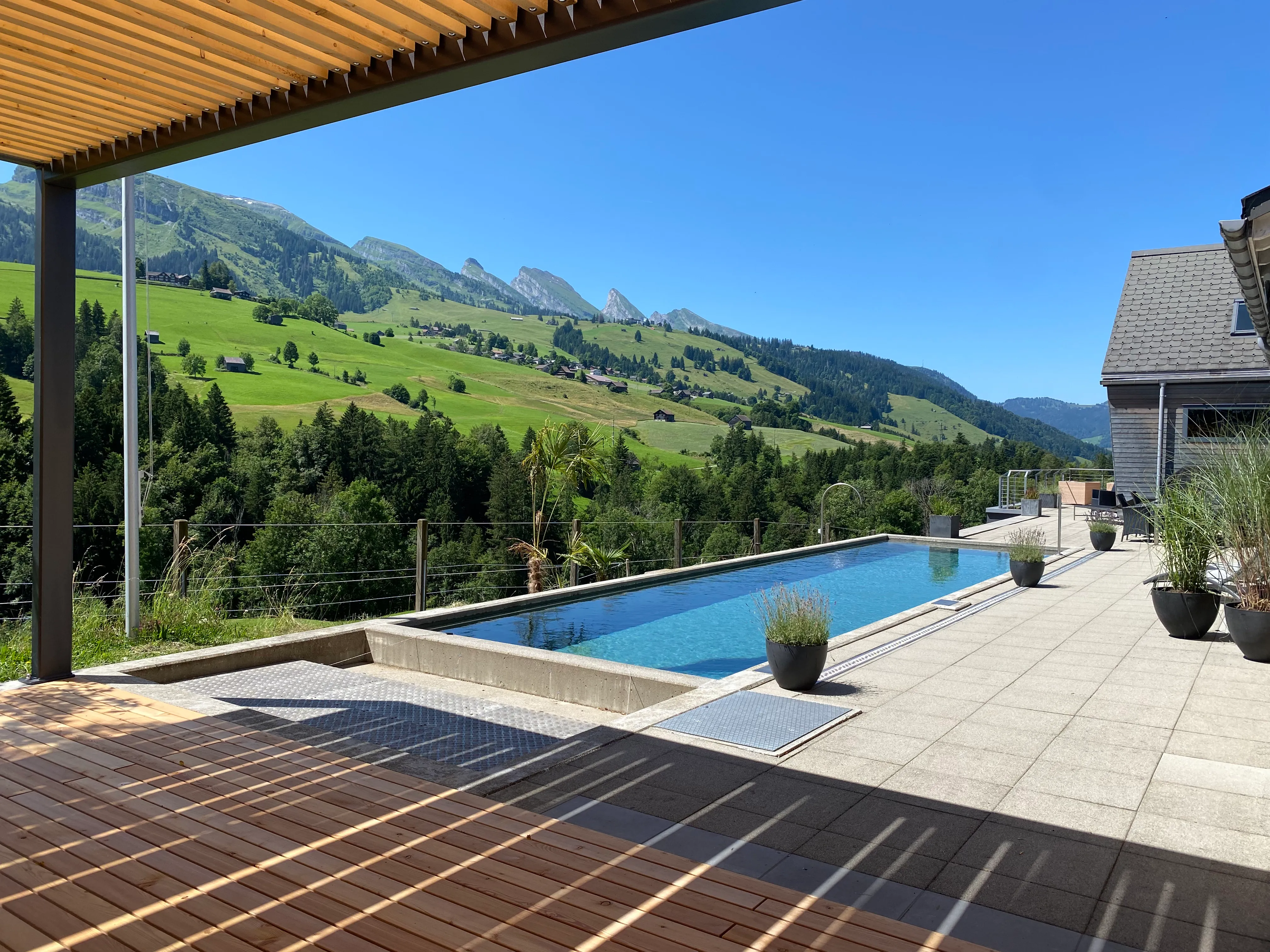 In die Anlage integrierter Pool neben der Holzpergola im Garten.